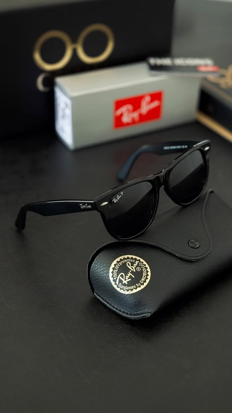 Black Ray-Ban sunglasses with a leather case and product packaging on a dark surface