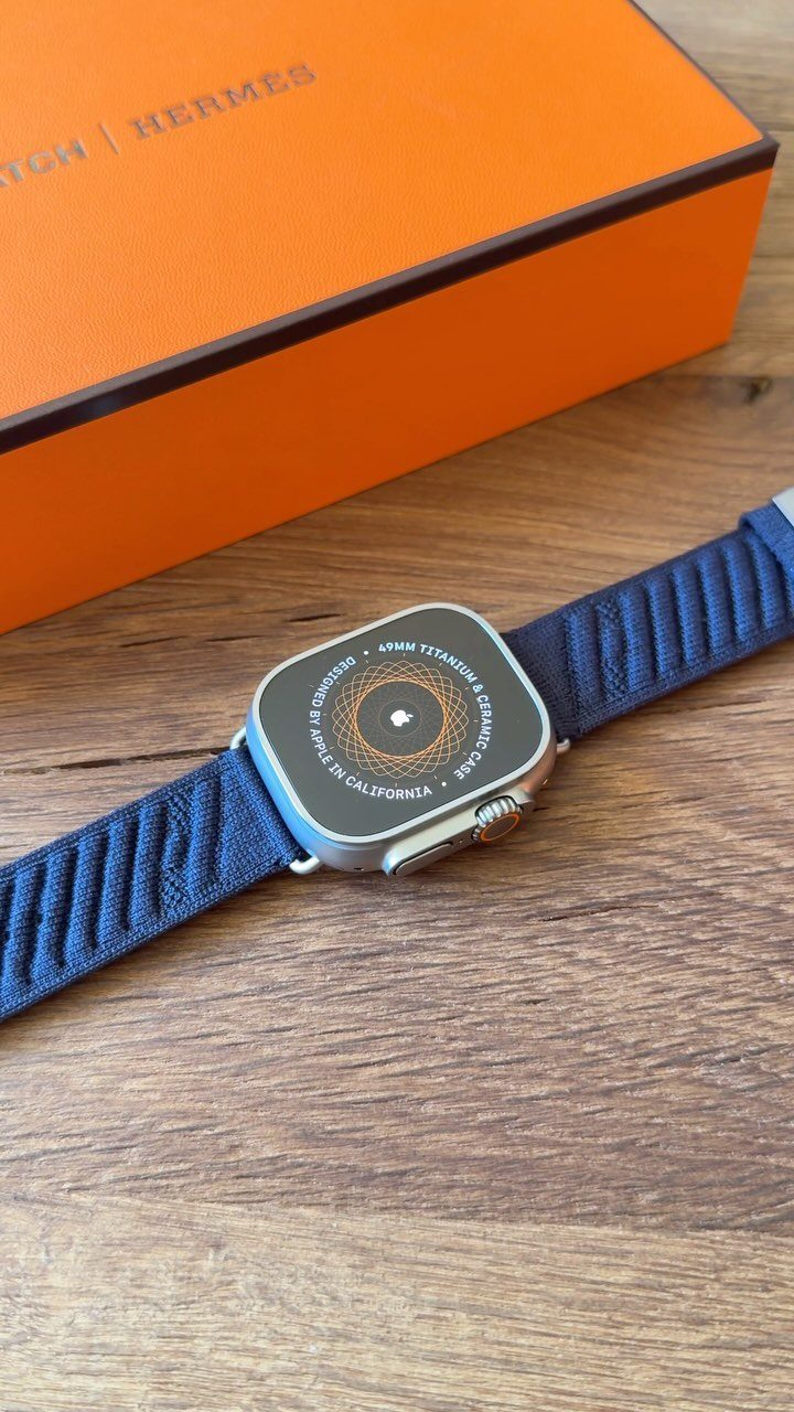 Silver smartwatch with blue strap next to an orange luxury gift box