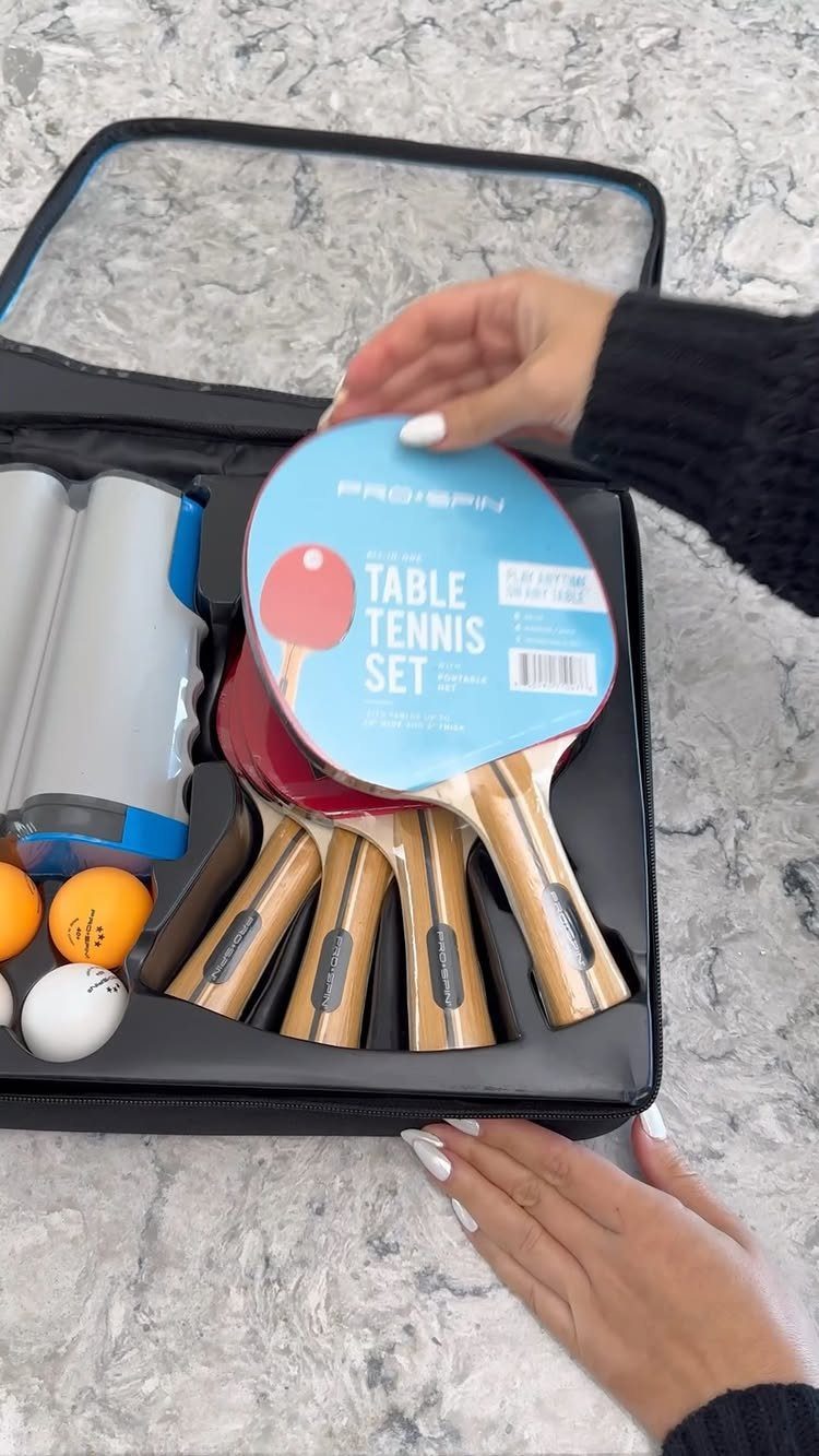 Table tennis set in a black case with red paddles and ping pong balls.