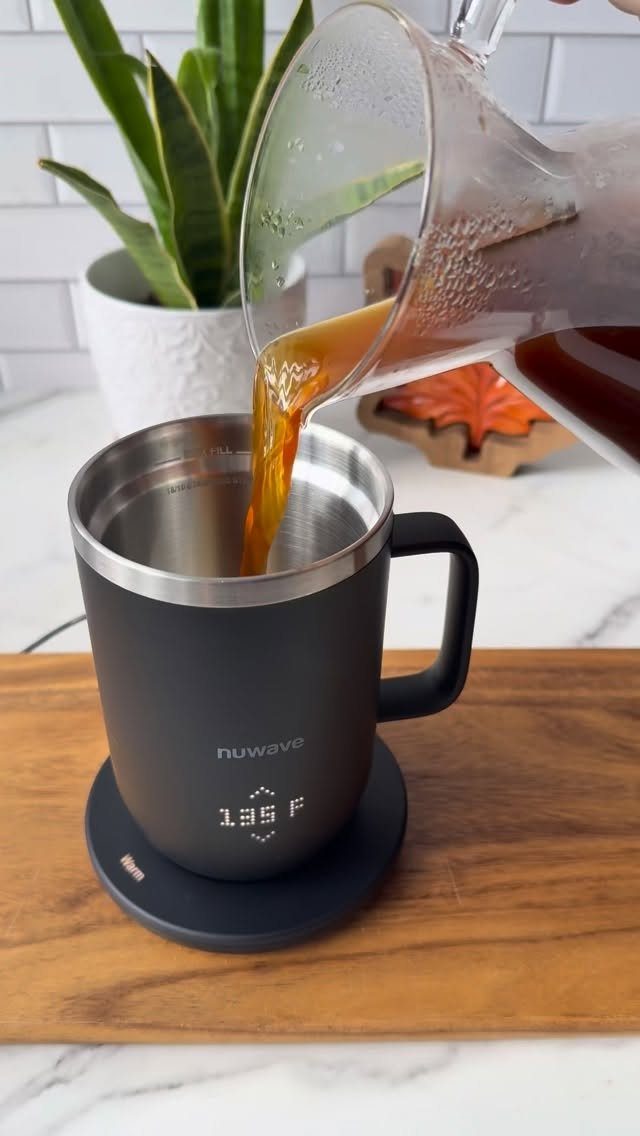 Black NuWave smart mug on a warming coaster with coffee being poured in.