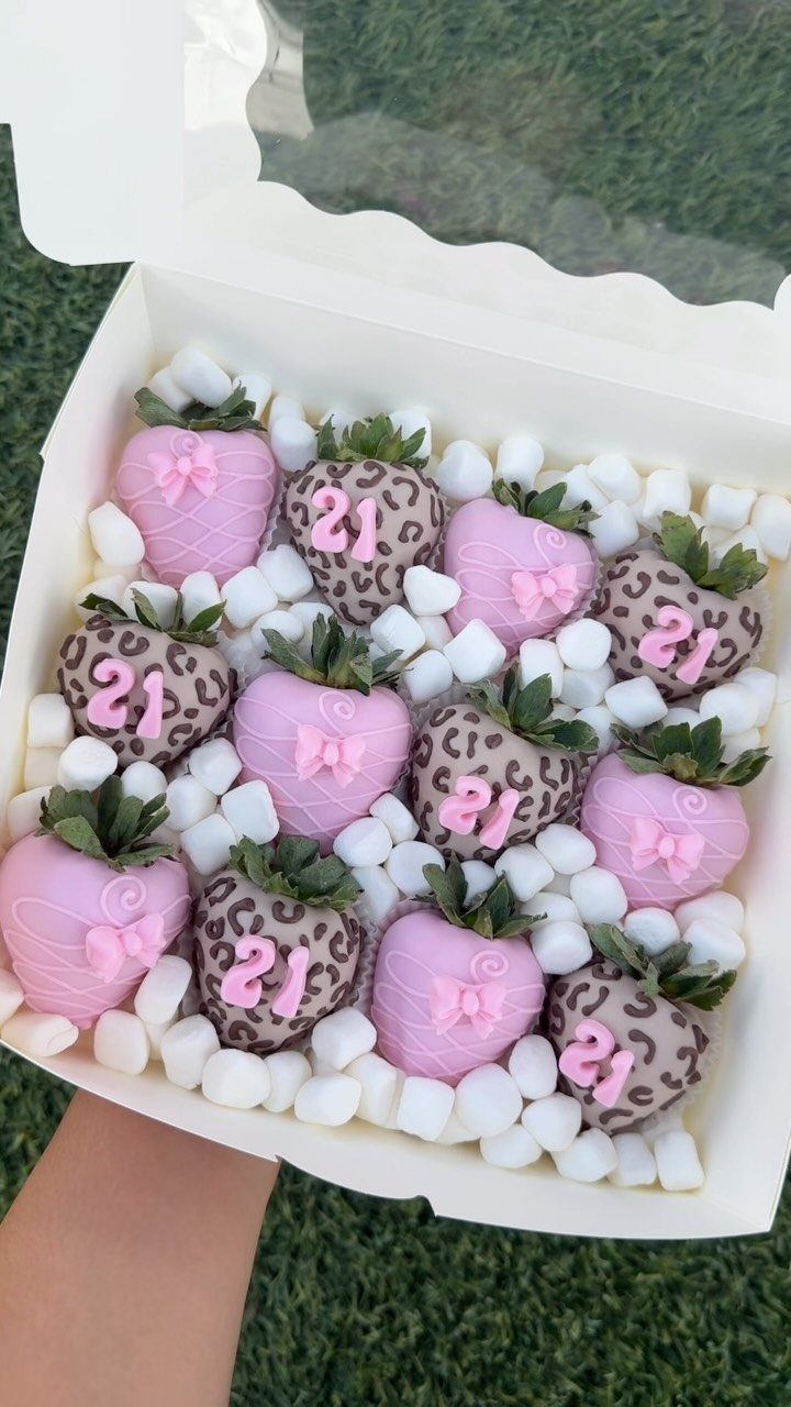 Chocolate-covered strawberries in pink and leopard print patterns inside a white gift box.