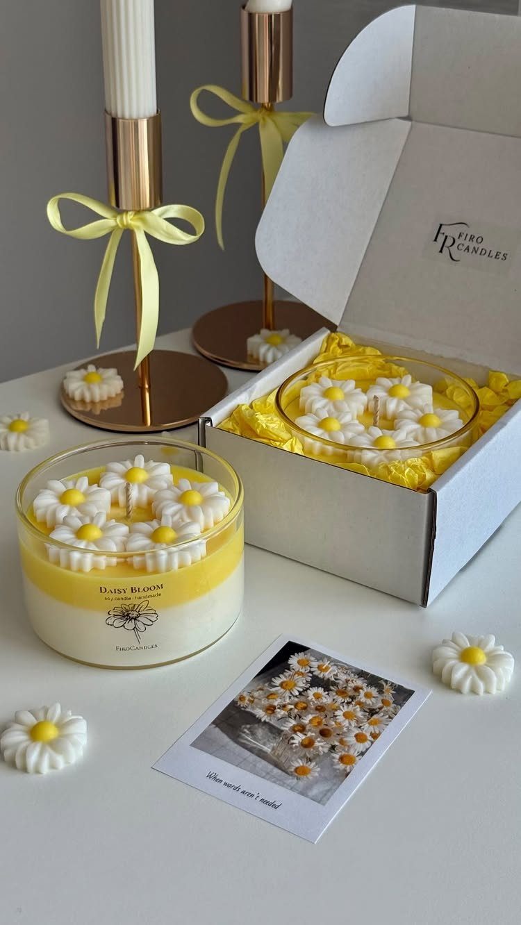 Yellow daisy candles in a gift box with gold holders and yellow ribbons.