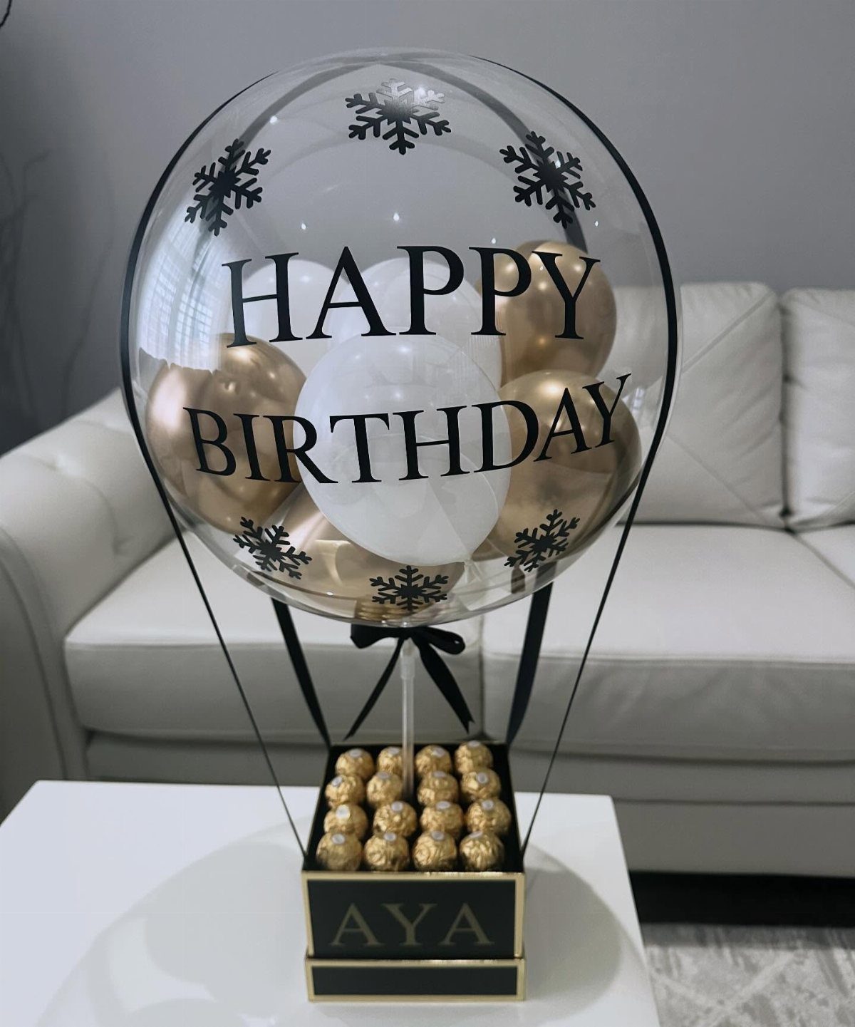 Birthday gift featuring a large clear balloon over a box of gold chocolates