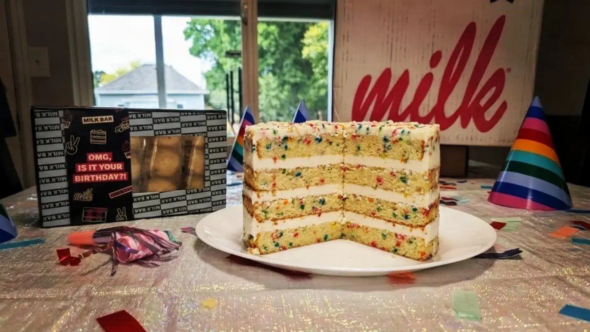 Confetti birthday cake on a white plate with Milk Bar branding in background
