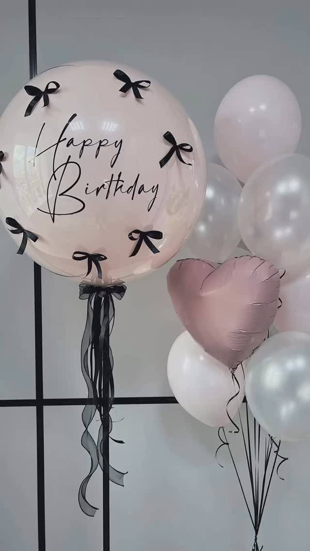 Birthday balloon bouquet with a large personalized clear balloon and pink heart balloon.