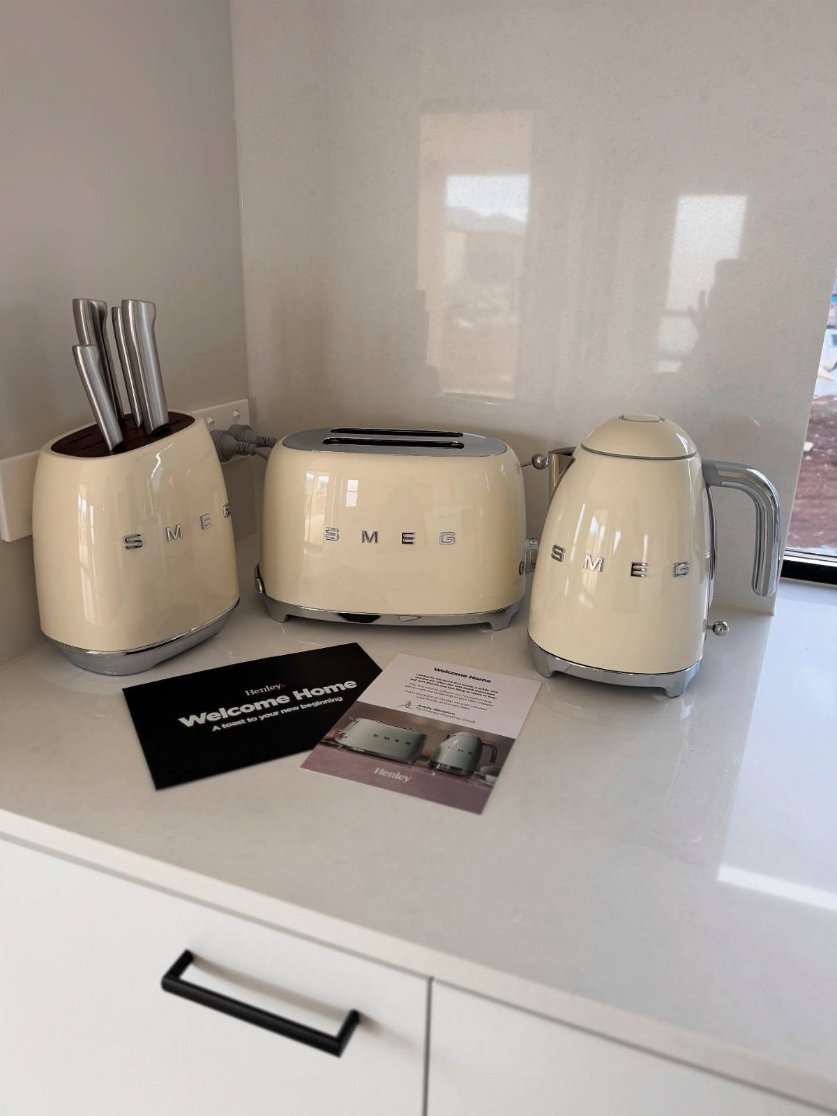 Cream Smeg kitchen appliances including a toaster and kettle on a white counter.