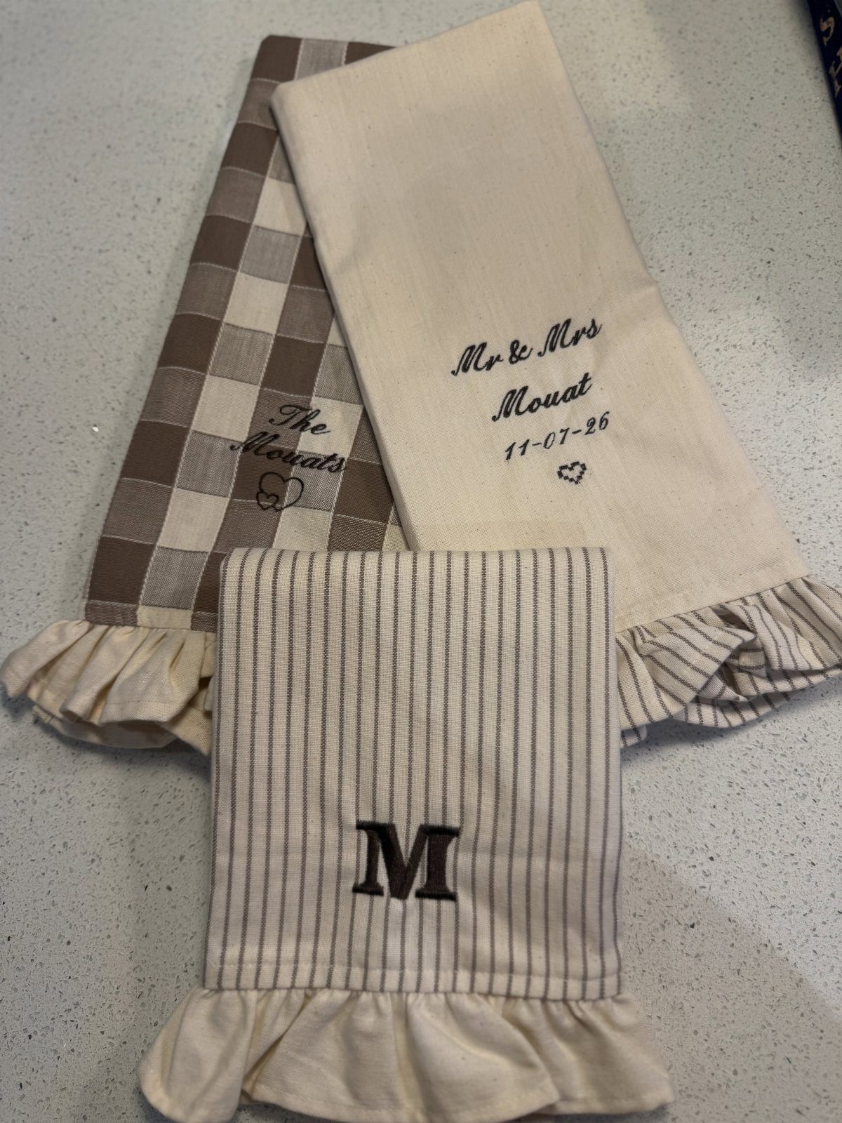 Personalized kitchen towels with ruffles in checkered, cream, and striped patterns.
