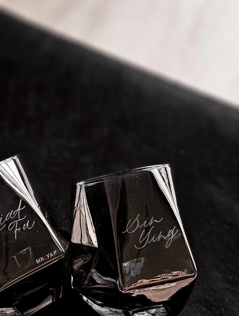 Two square whiskey glasses with cursive names engraved on the clear glass sides.