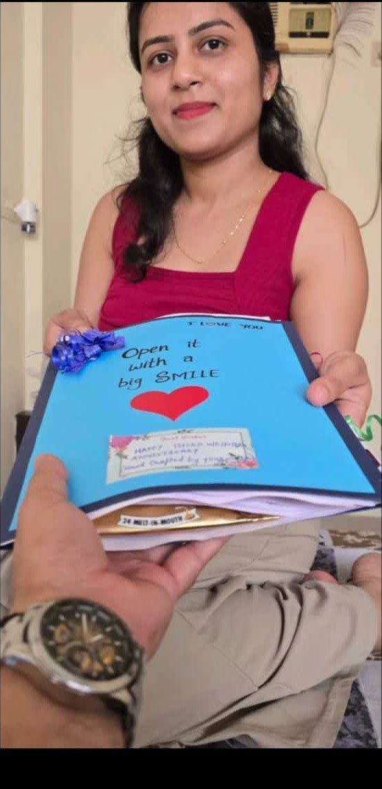 Woman holding a blue handmade anniversary scrapbook with a red heart for her husband