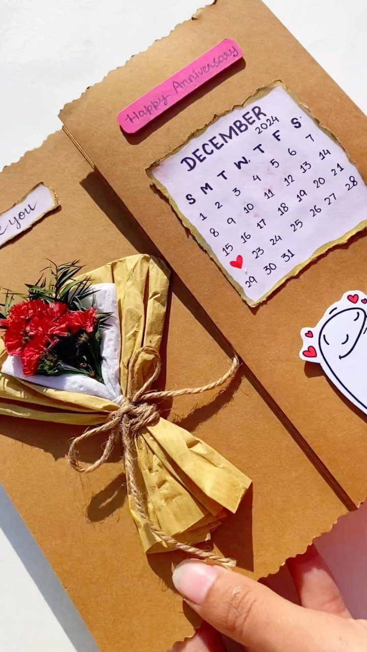 Handmade anniversary card with a December calendar and small red flower bouquet.