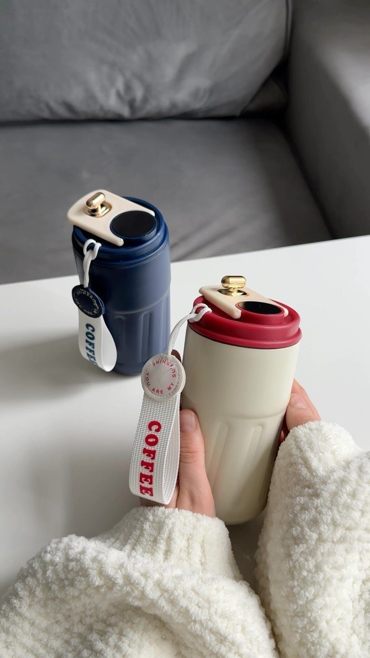 Two insulated coffee tumblers in navy and cream on a white table.