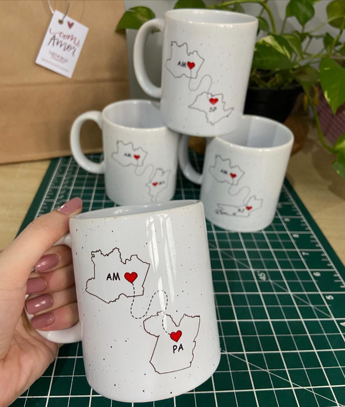 White speckled ceramic mugs featuring a map of Brazilian states with red hearts.