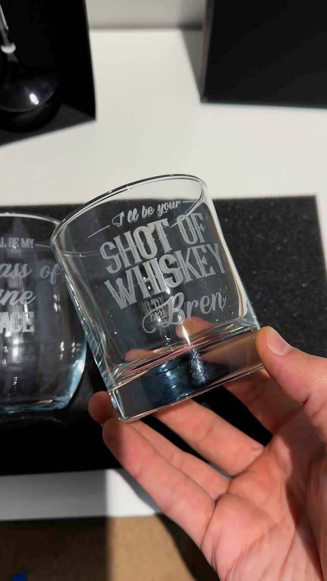 Engraved glass whiskey tumbler with romantic text held by a person's hand.
