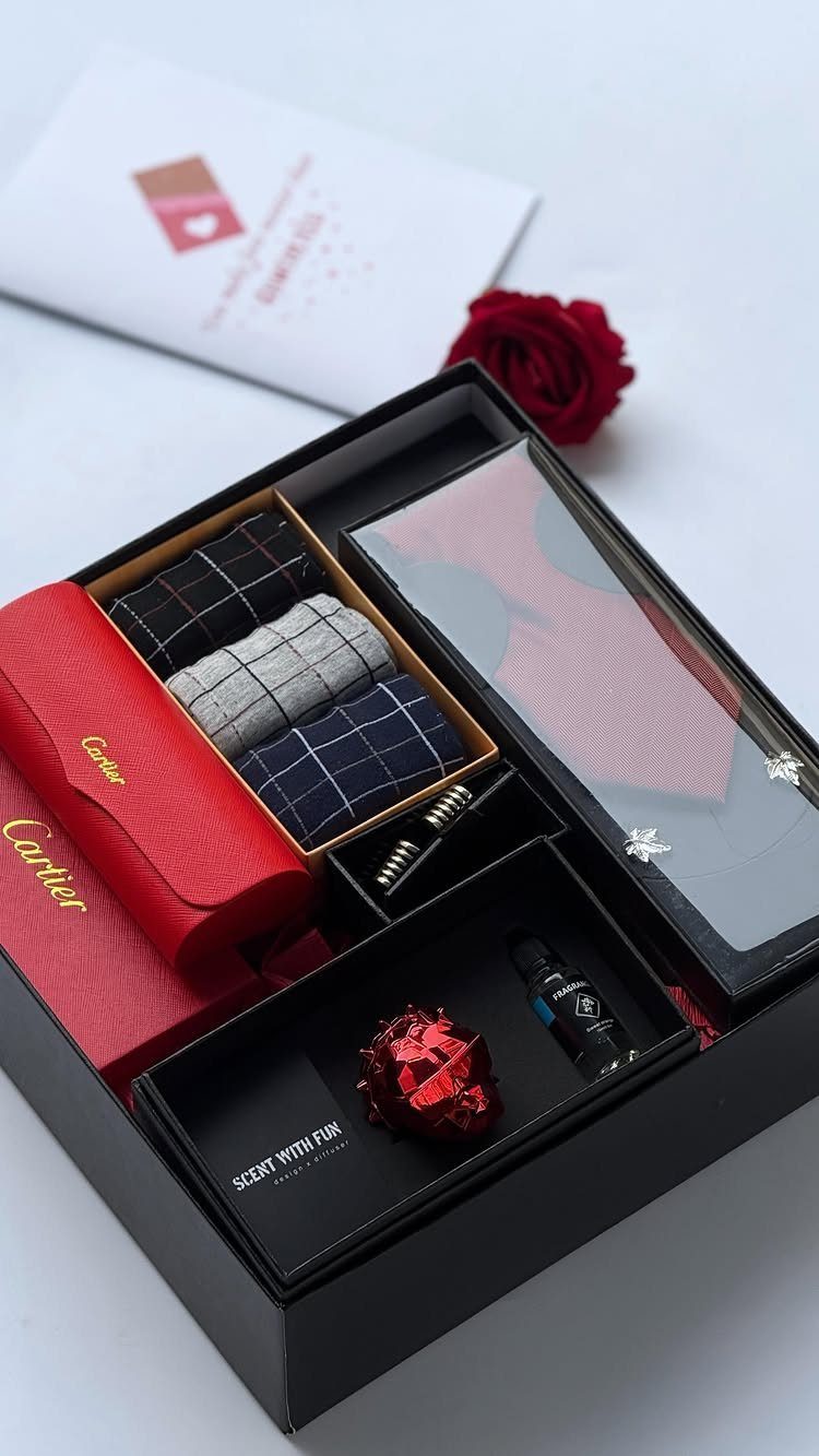 Gift box with red tie, patterned ties, Cartier box, and silver cufflinks.