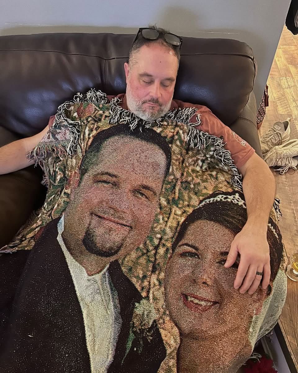Man resting on a sofa covered by a personalized photo blanket of a couple.