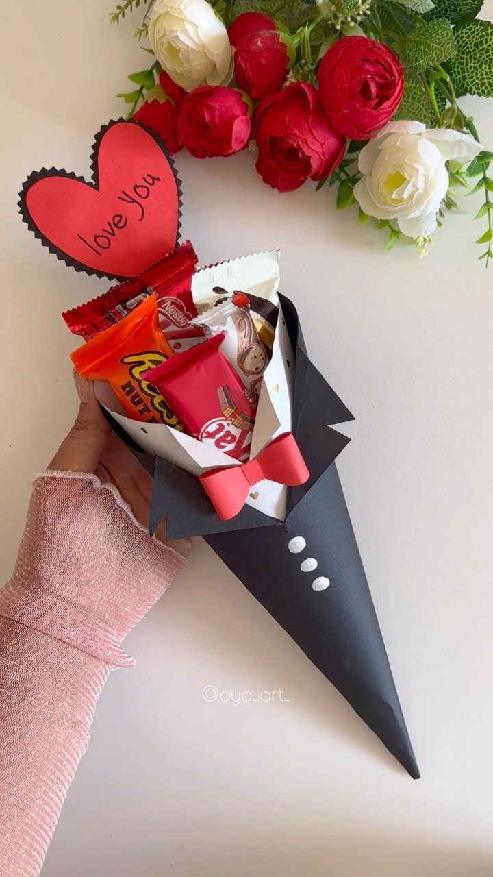 Tuxedo-shaped candy bouquet with a red heart and red and white flowers.