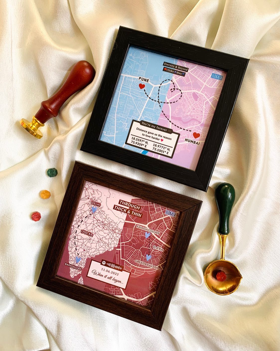 Two framed custom map artworks with heart paths on white satin fabric.