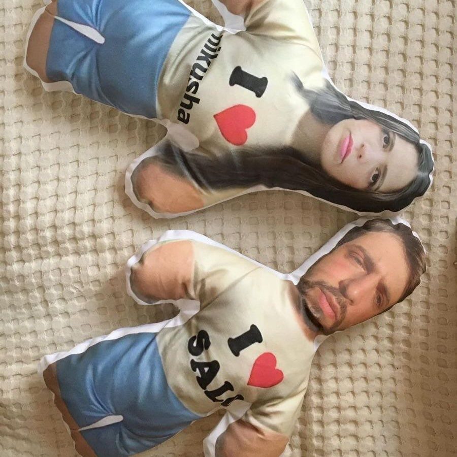 Two custom body-shaped pillows featuring photos of a couple on a white blanket.