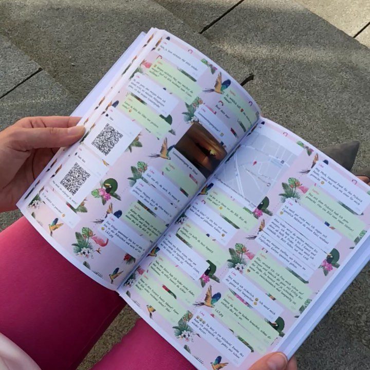 Open scrapbook with colorful notes, photos, and QR codes held by a person.