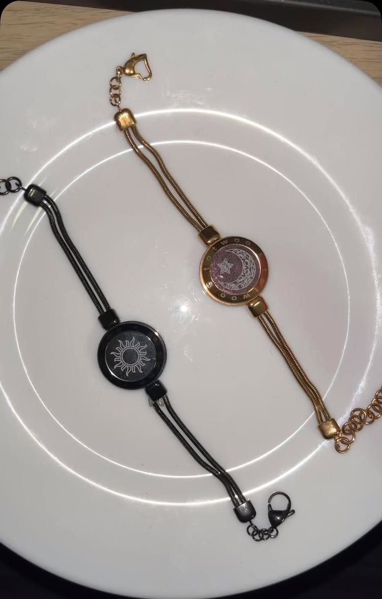 Two cord bracelets with sun and moon charms resting on a white plate.