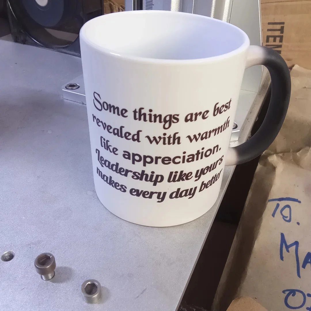White ceramic mug with leadership quote and grey handle on metallic surface