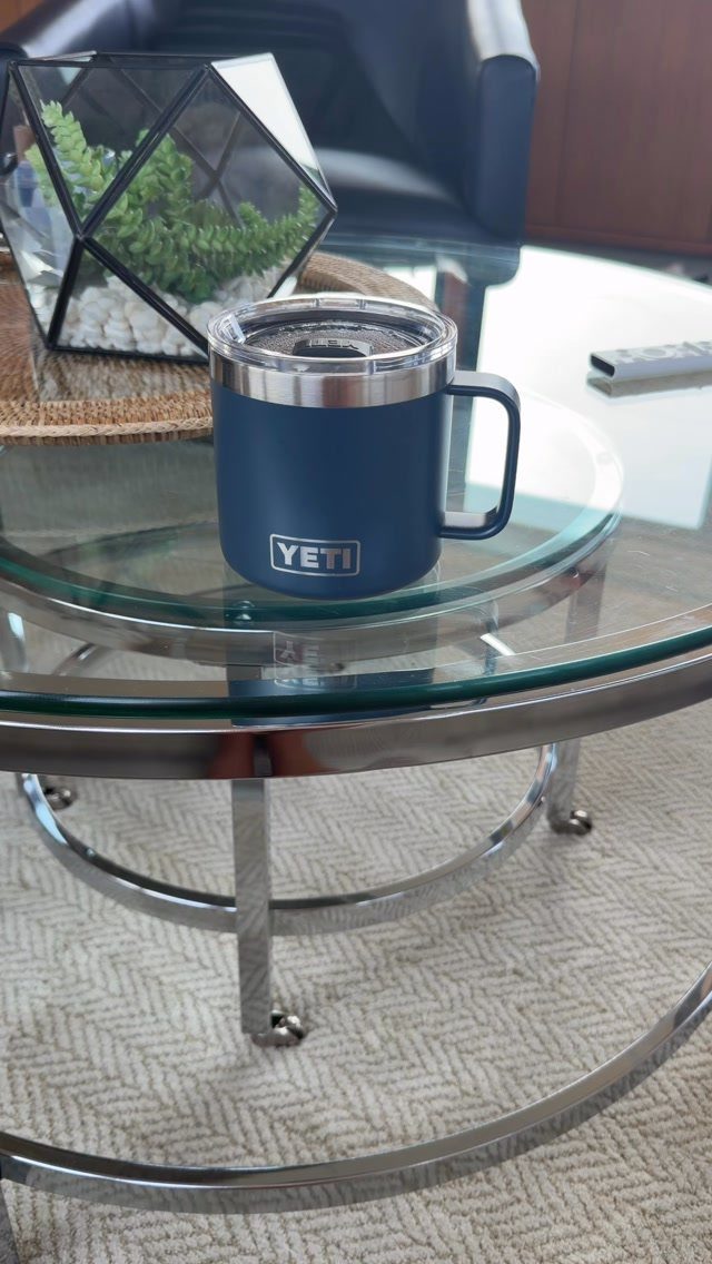 Navy blue YETI insulated mug on a glass coffee table next to a terrarium