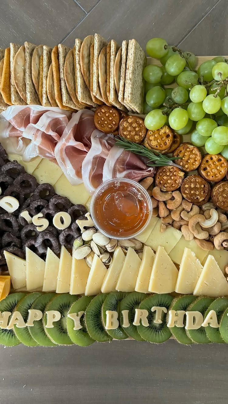 Charcuterie board with meats, cheeses, and fruits spelling Happy Birthday with crackers.