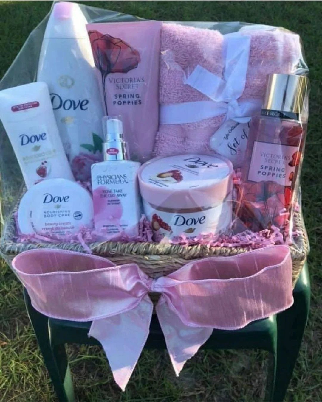 Wicker gift basket with pink bow containing Dove and Victoria's Secret beauty products.