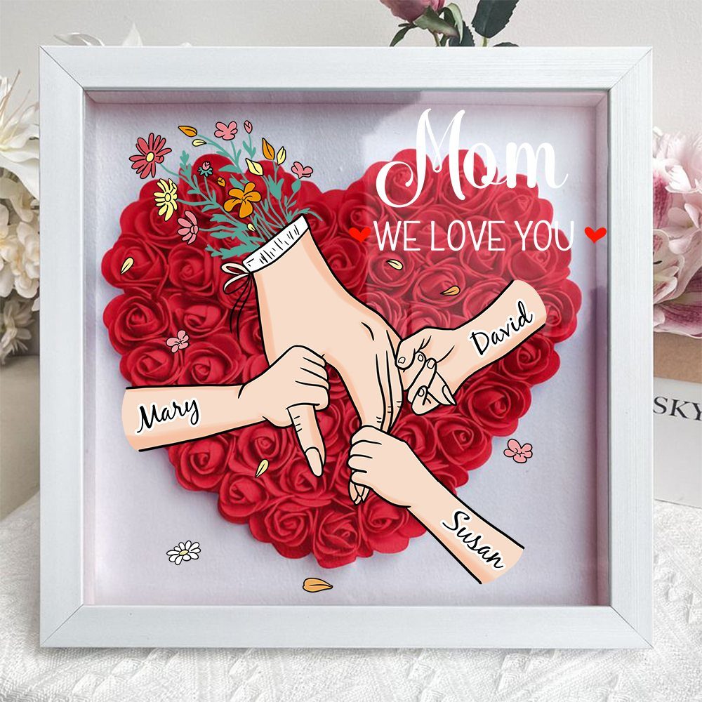 Shadow box with red rose heart and illustration of family hands joined together.