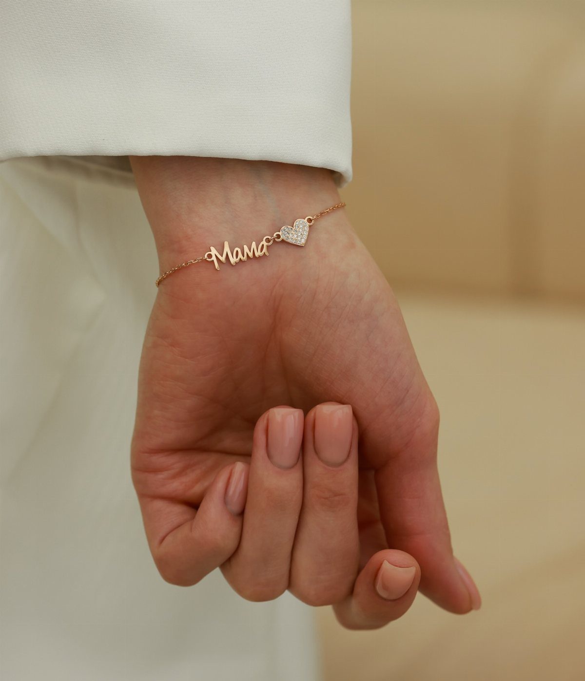 Rose gold bracelet with 'Mama' script and heart charm on a wrist