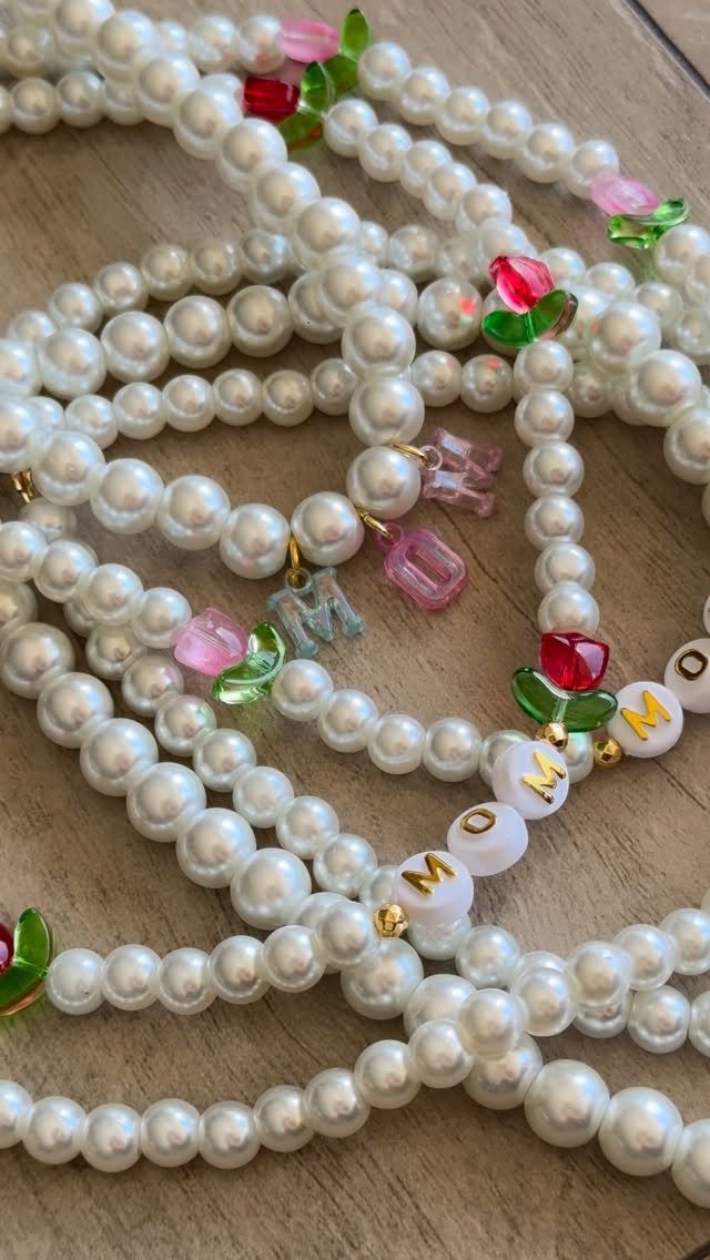 Pearl necklaces with fruit beads and letter beads spelling MOM on wood.