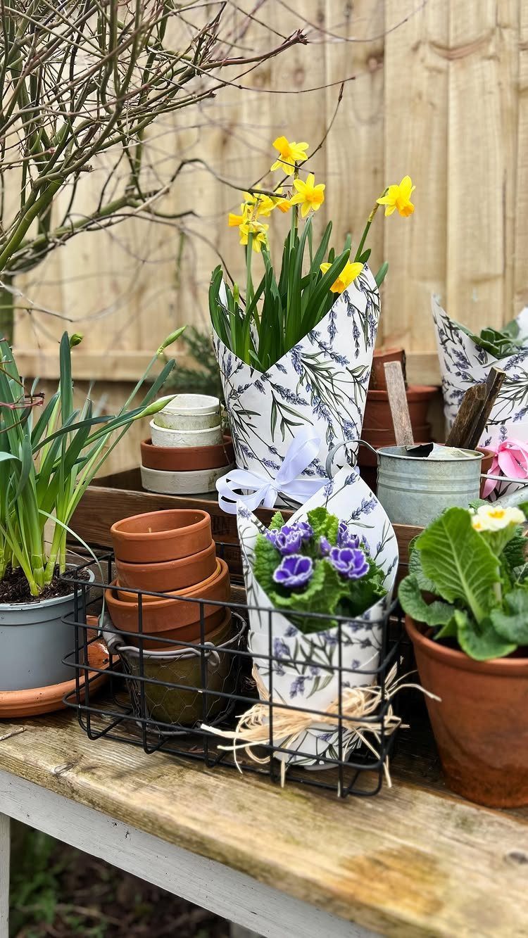 Yellow daffodils and purple pansies wrapped in decorative paper on a wooden table.