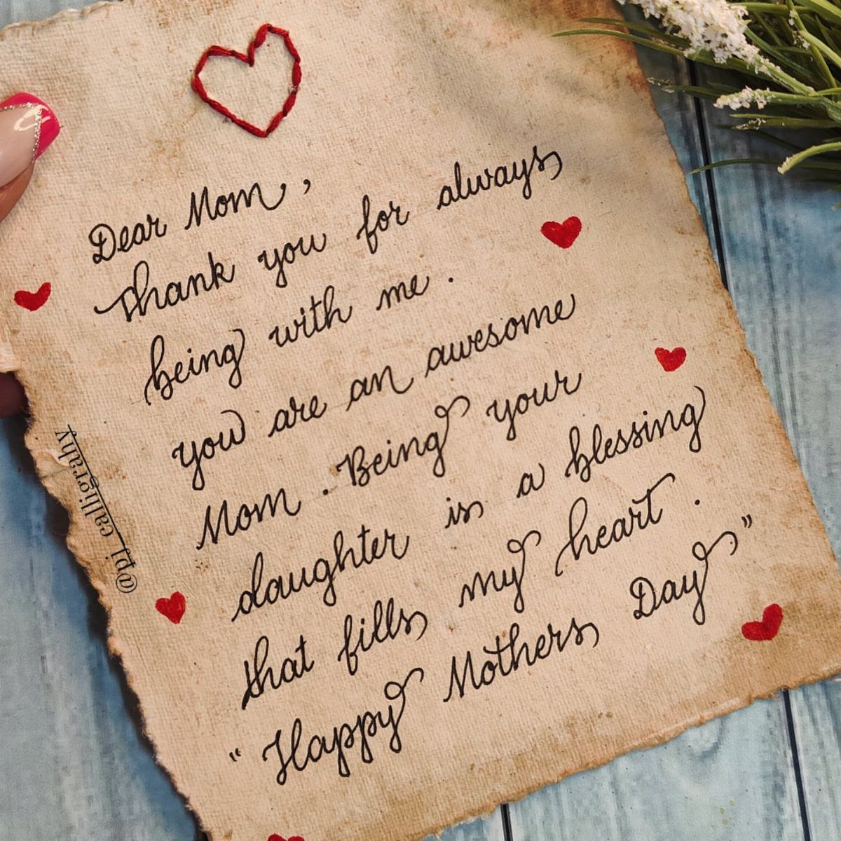 Handwritten Mother's Day letter on aged parchment paper decorated with small red hearts.