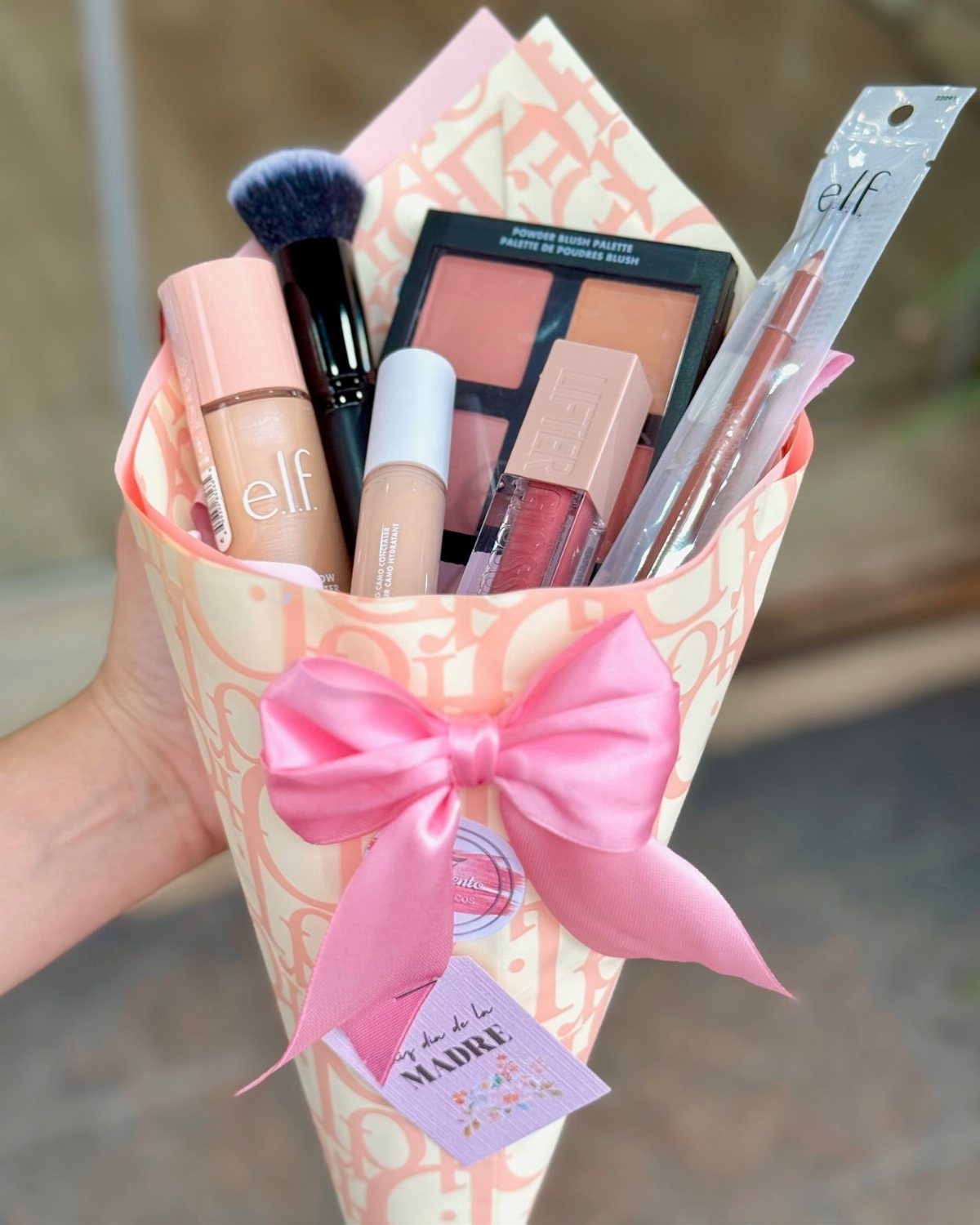 Makeup product bouquet wrapped in cream paper with a pink satin bow