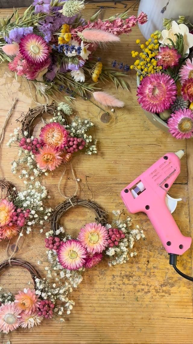 Small grapevine wreaths with pink dried flowers and a pink glue gun.