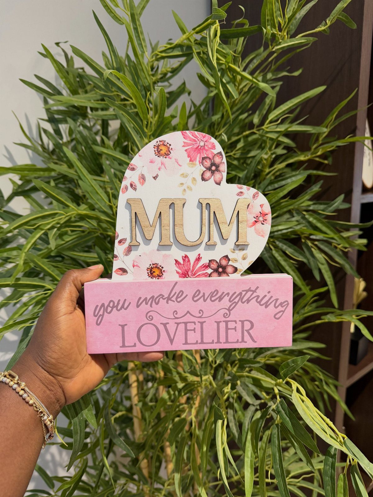 Wooden heart plaque for Mum with floral designs and pink base held by hand.
