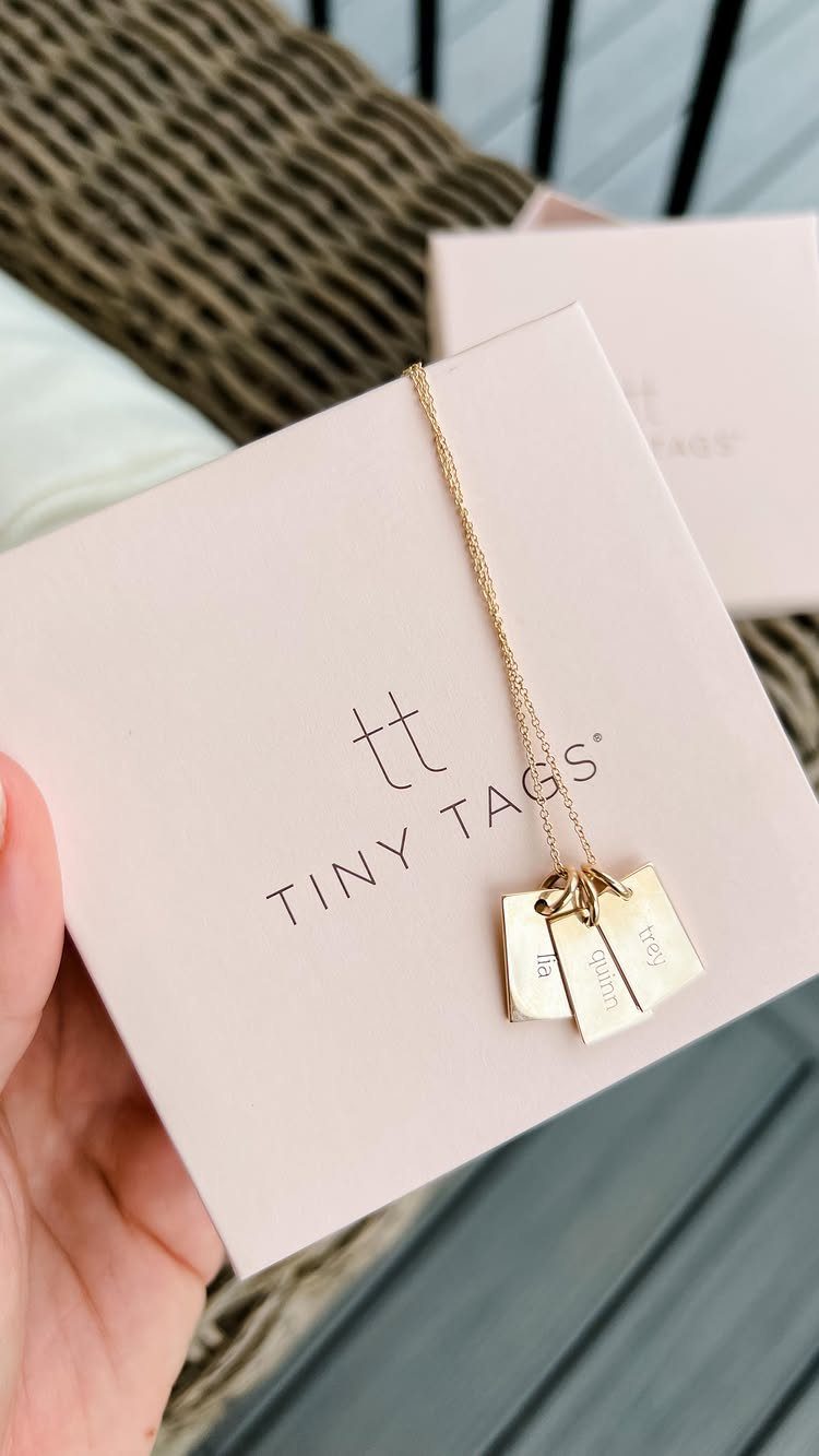 Gold necklace with three small rectangular tags on a pink Tiny Tags card