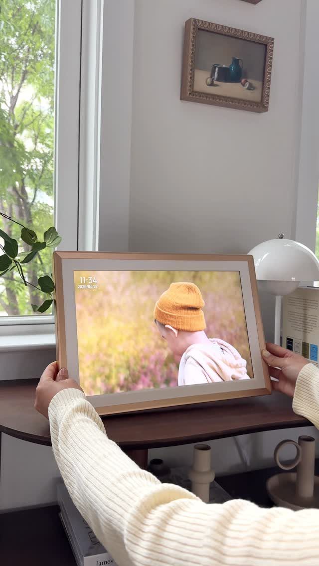 Digital photo frame with wooden border showing a child in an orange hat.