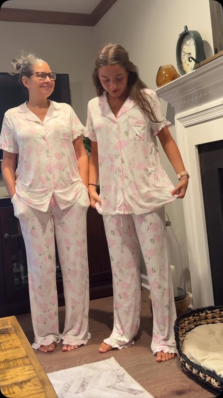 Woman and daughter wearing matching white and pink floral pajama sets in a home.