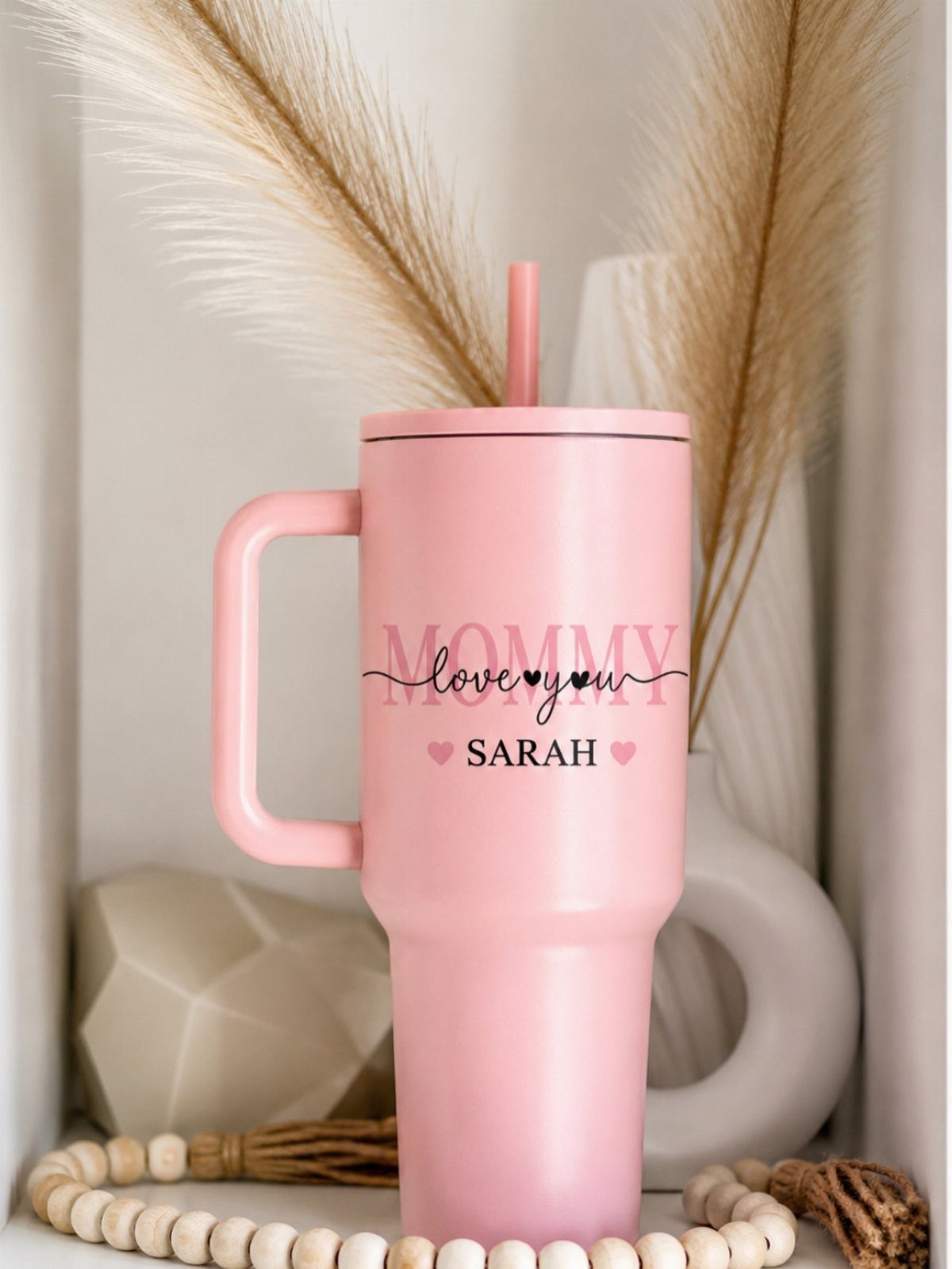 Pink personalized tumbler with Mommy love you Sarah text and heart accents.