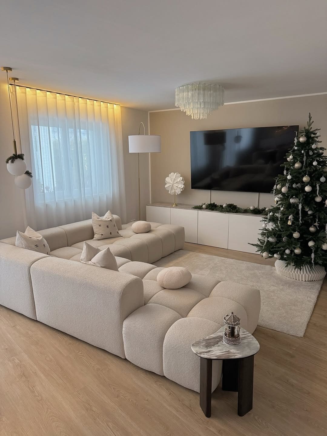 Modern living room with cream modular sofa and a minimalist decorated Christmas tree.