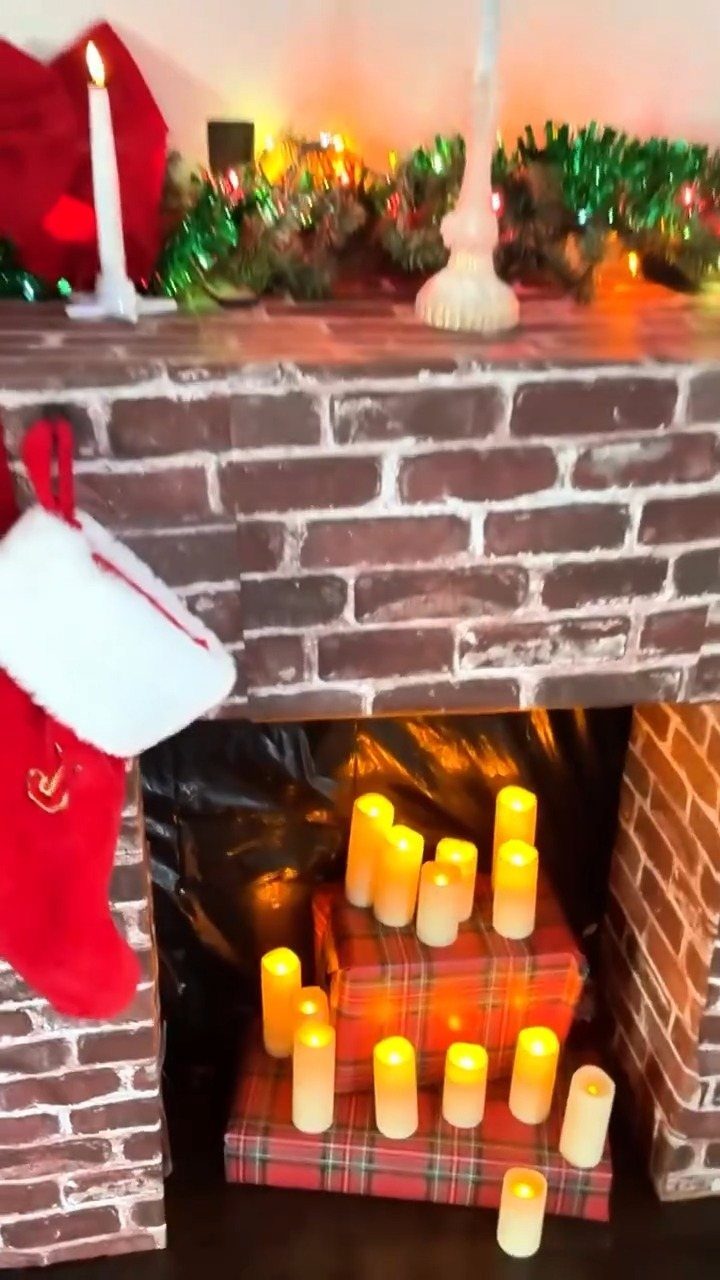 DIY faux brick fireplace with red stocking, green garland, and glowing LED candles.