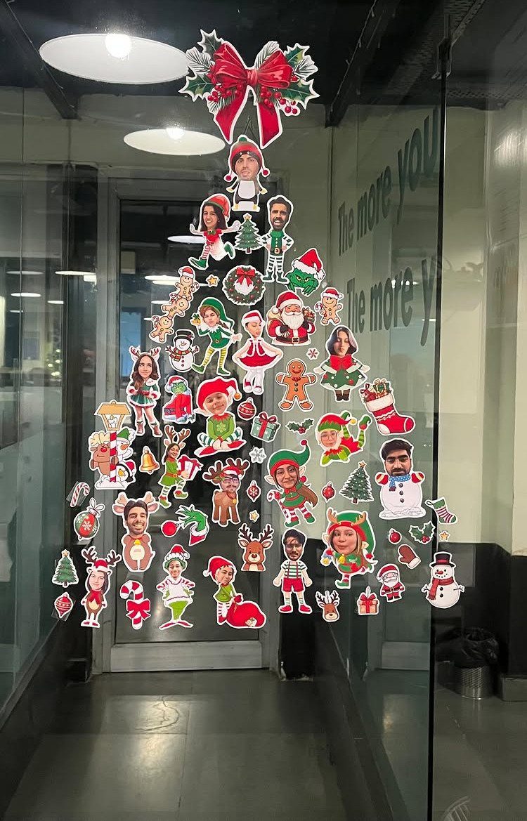 Christmas tree made of employee face cutouts on a glass office door