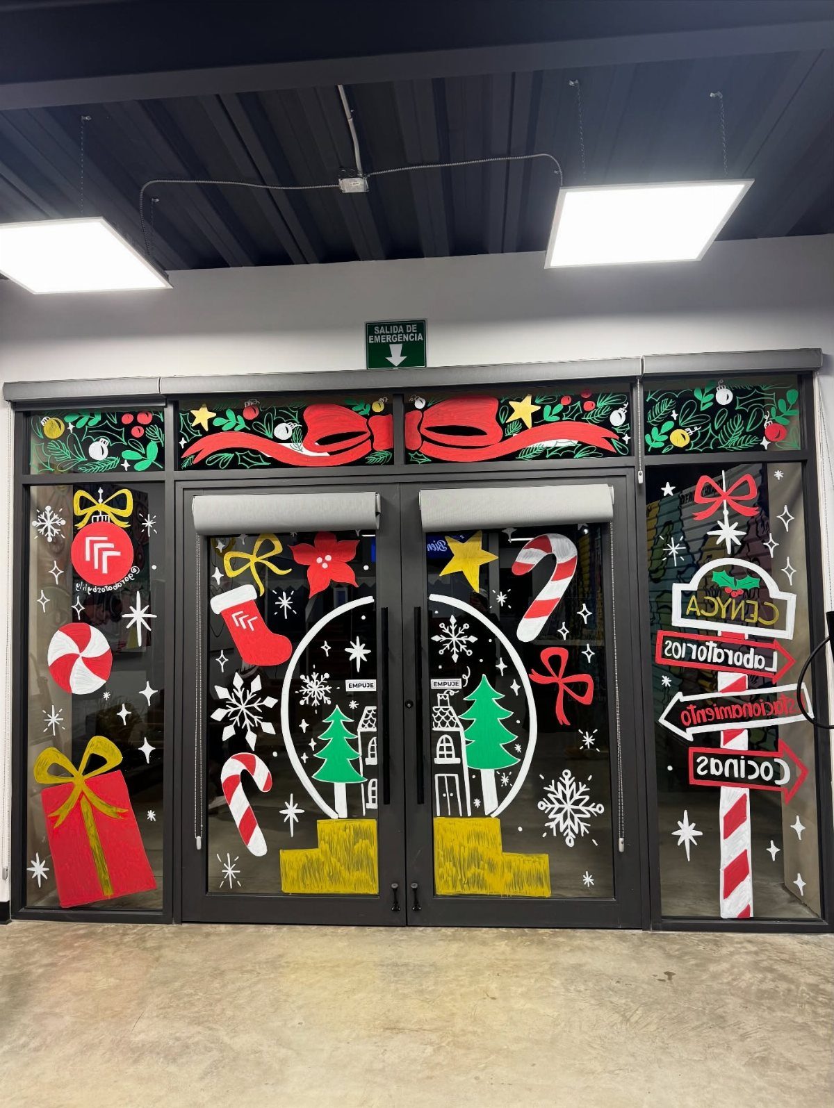 Glass office doors decorated with colorful Christmas decals like candy canes and snowflakes.