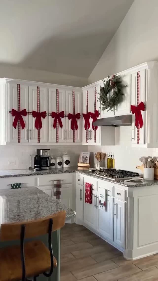 White kitchen cabinets decorated with red plaid ribbons, bows, and a Christmas wreath.