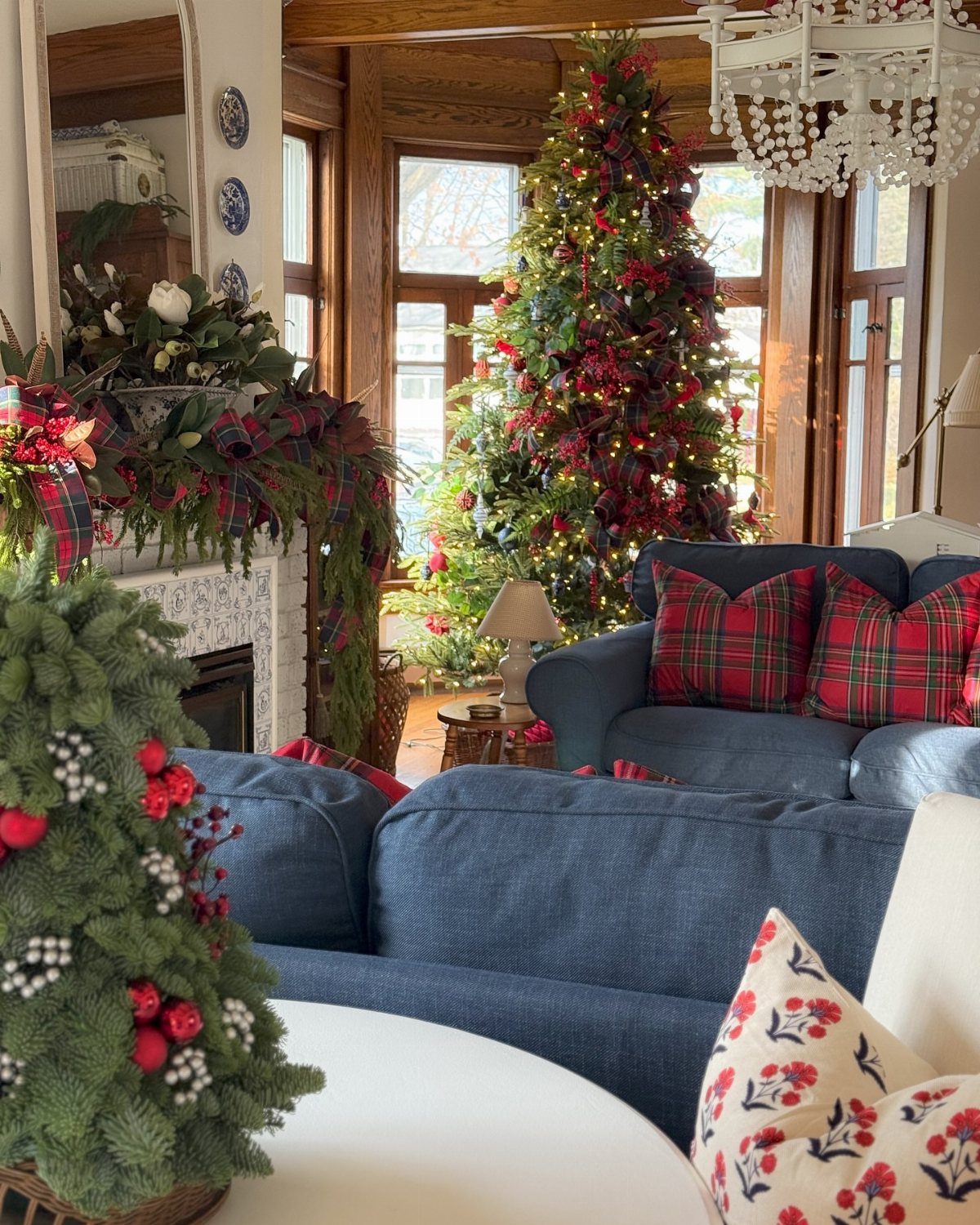 Christmas living room with a decorated tree and plaid ribbons on the mantel.