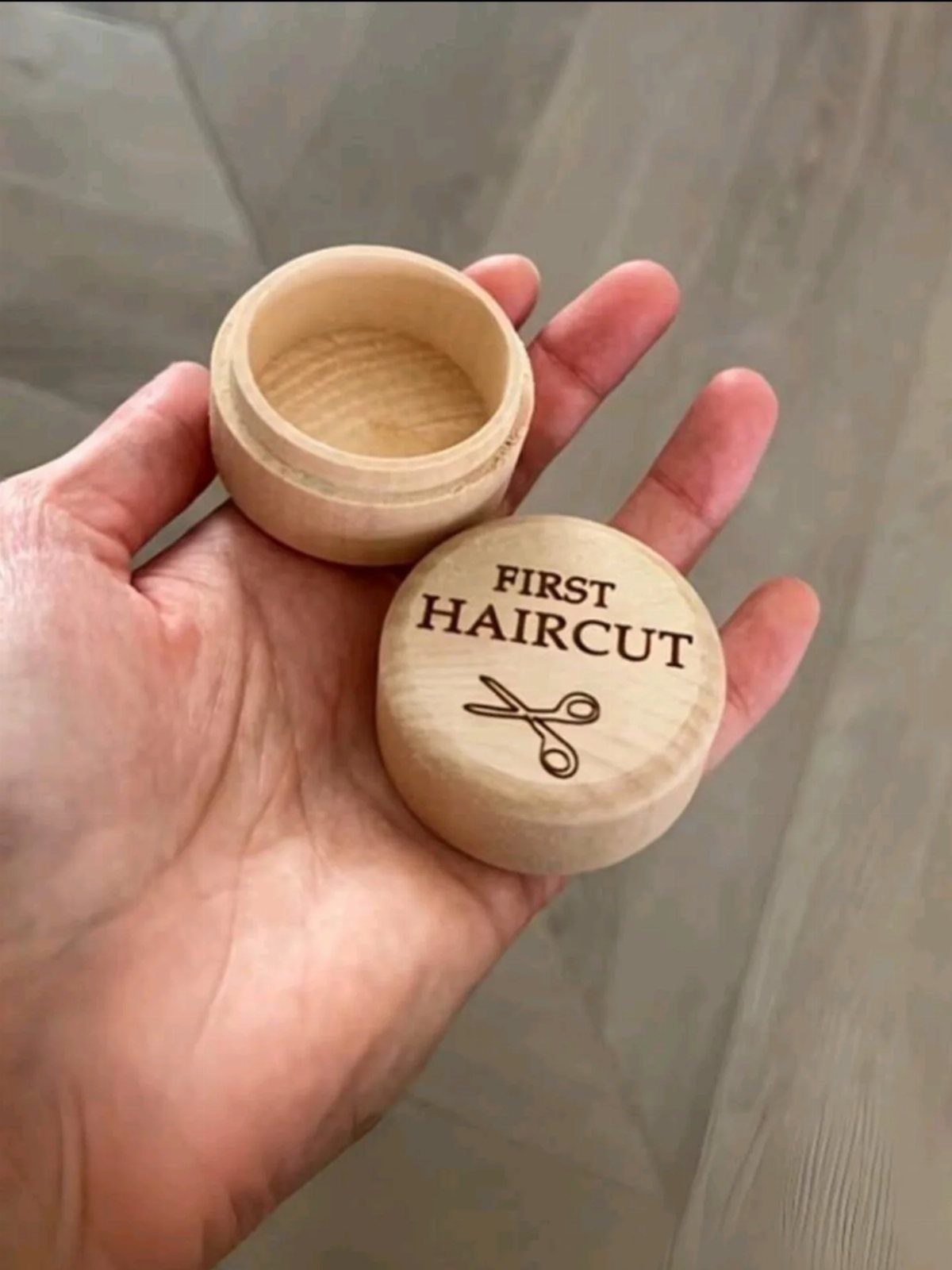 Small wooden keepsake box for a first haircut held in a hand.