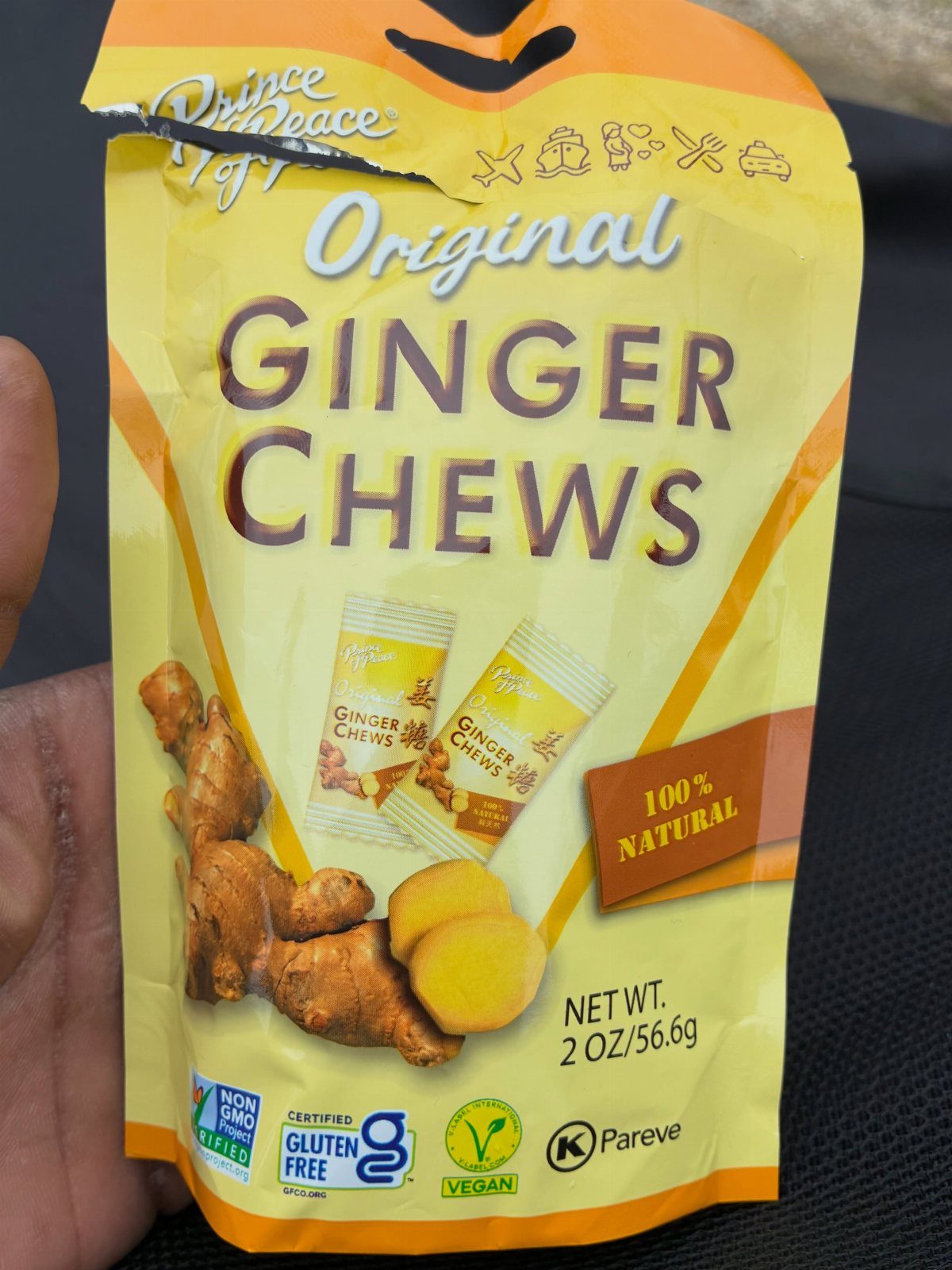 Yellow package of Original Ginger Chews held by a hand against a dark background