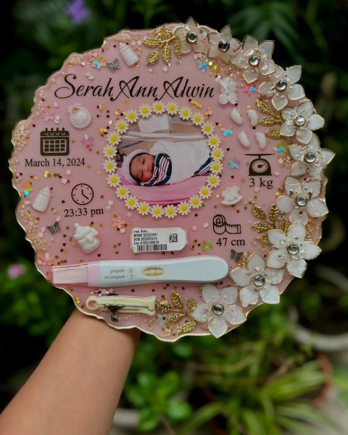 Pink circular baby keepsake sign with photo, birth details, and floral decorations.
