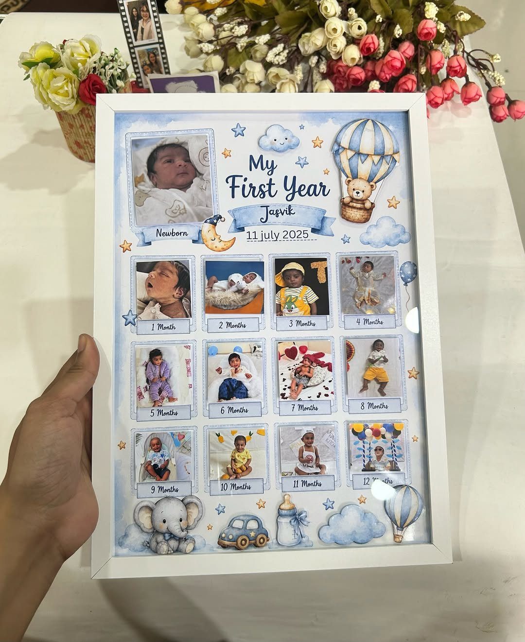 White photo frame displaying a baby's first year milestones with twelve monthly photos.